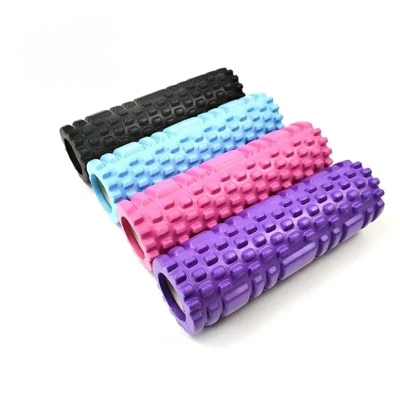 A set of four yoga rollers in black, blue, pink, and purple colors, each featuring a textured surface for muscle activation.
