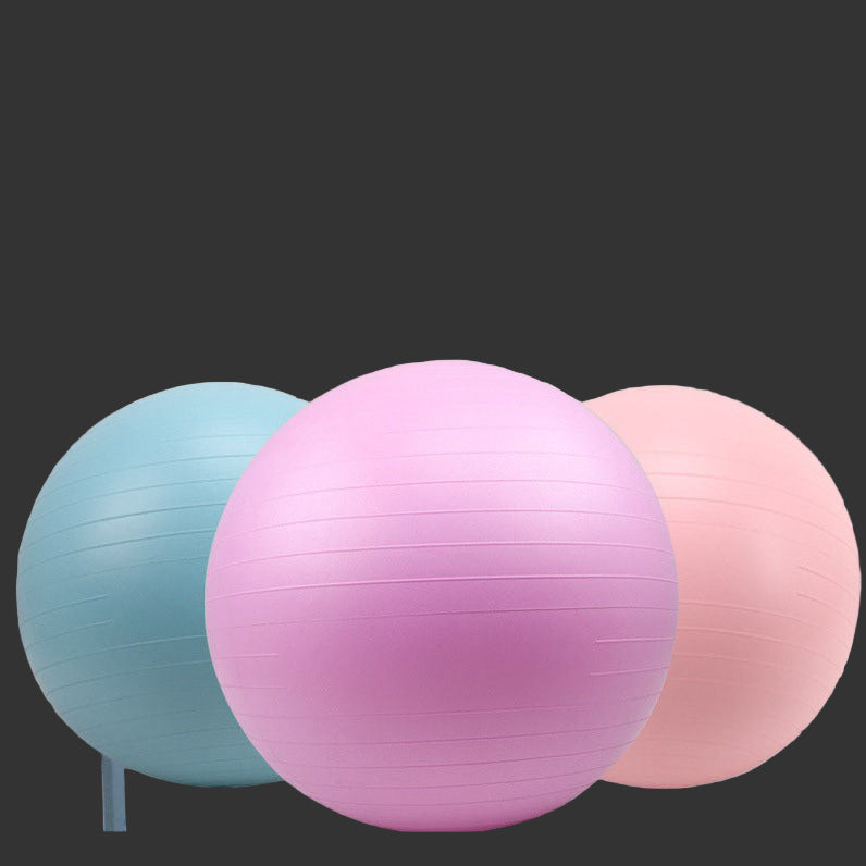 Three exercise balls in blue, pink, and red on a light wooden floor with a white curtain background.