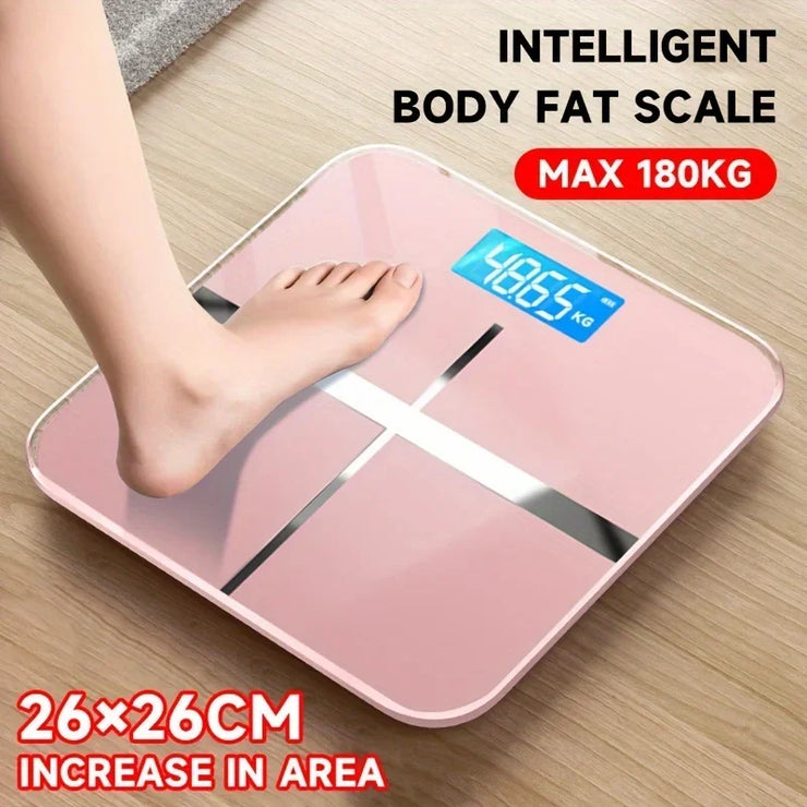 Pink intelligent body fat scale with digital display on a wooden floor.