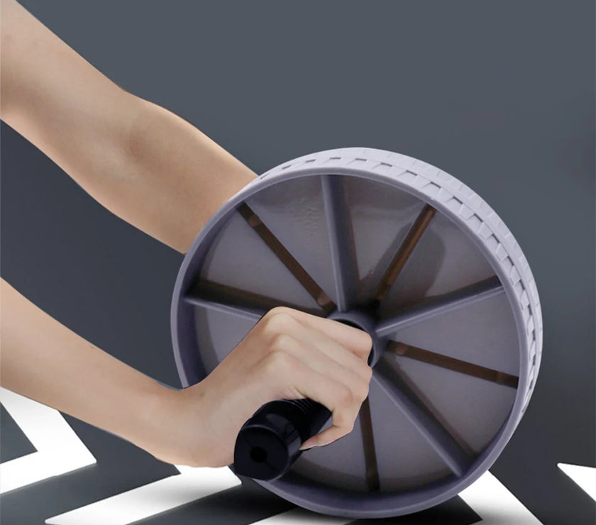 Hand using a purple exercise wheel against a dark background