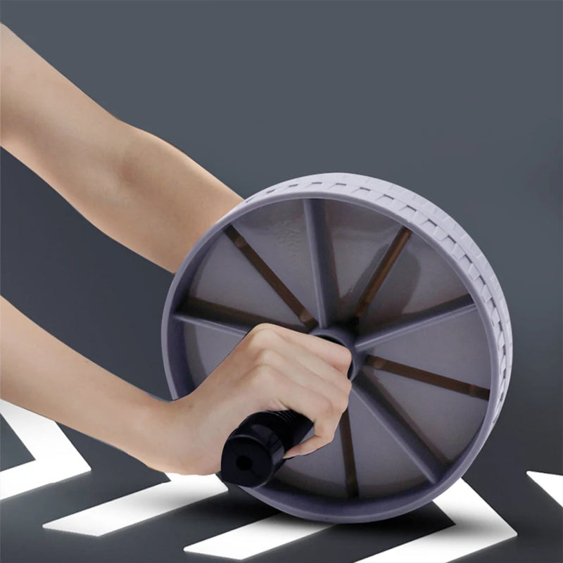 Hand using a purple exercise wheel against a dark background