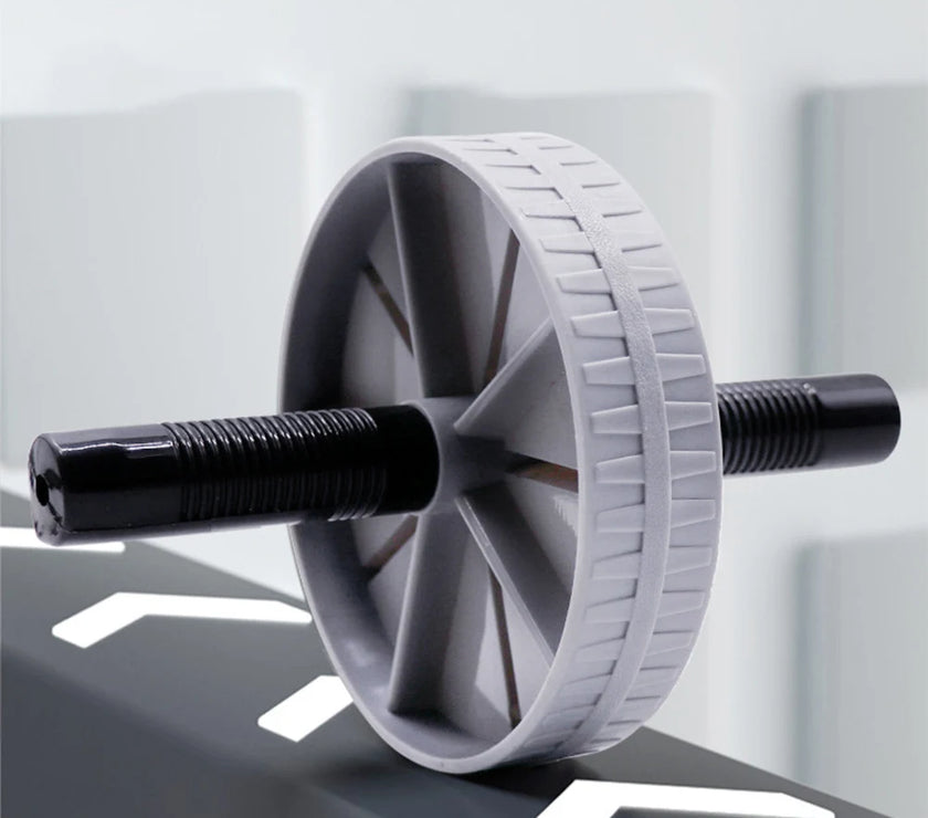 Gray exercise wheel with black handles on a reflective surface