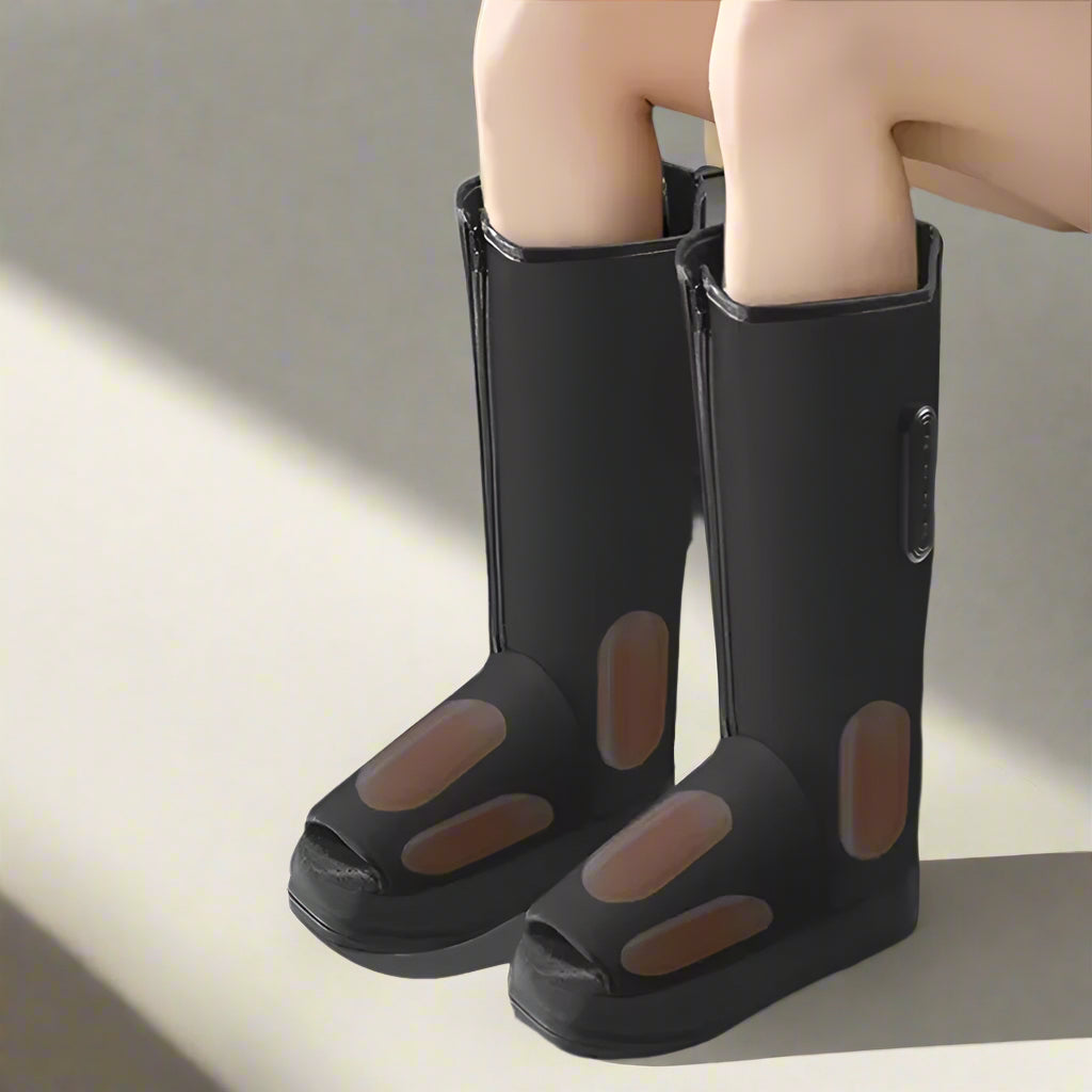 Black rubber boots with open-toe design worn by a person sitting on a couch.