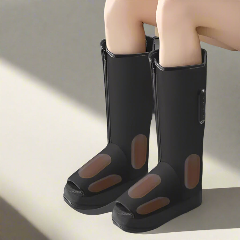 Black rubber boots with open-toe design worn by a person sitting on a couch.