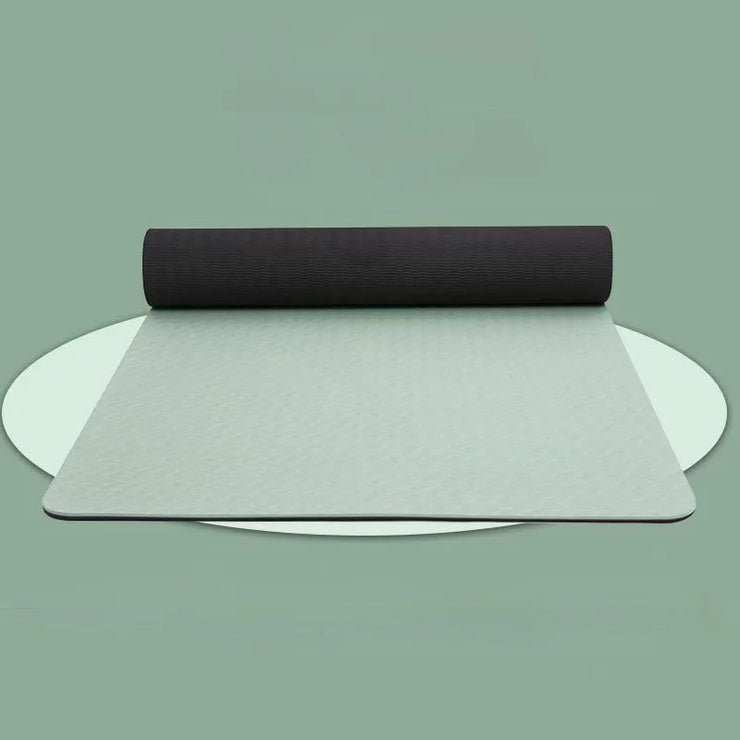 Two yoga mats, one black and one gray, on a light green background