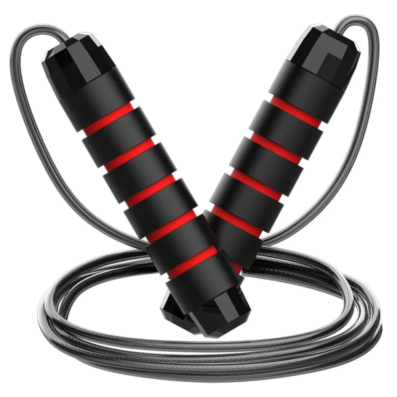 An adjustable jump rope with steel wire and black and red handles lying on a reflective surface.
