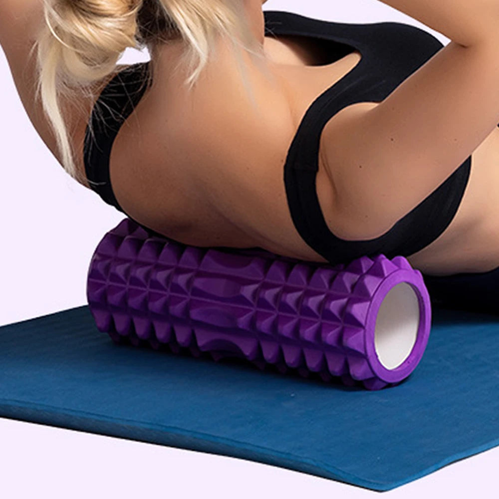 Person using a purple foam roller on a blue mat