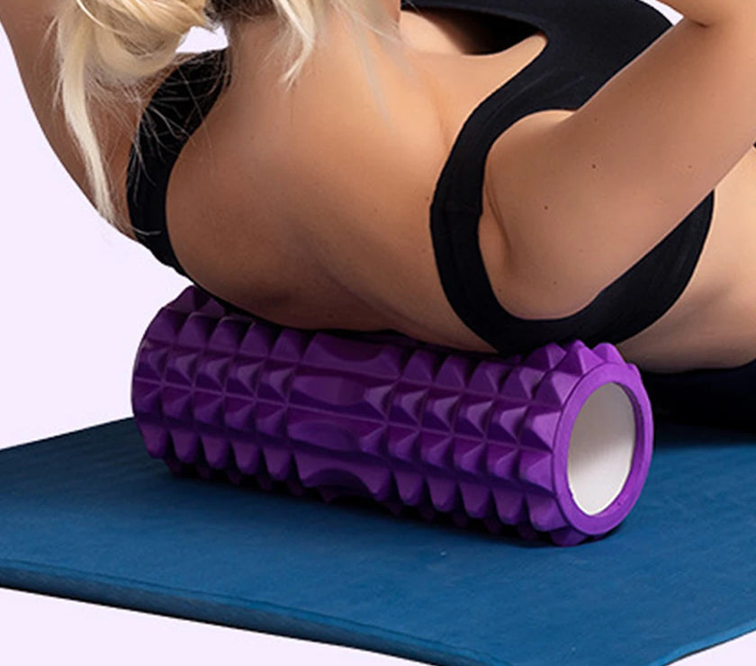 Person using a purple foam roller on a blue mat