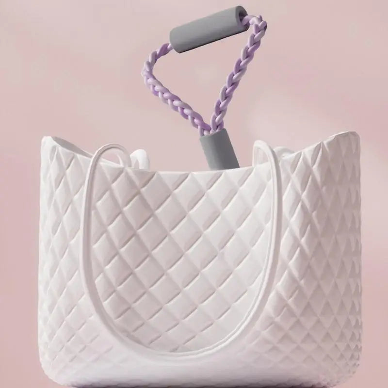 White quilted tote bag with a gray handle and purple braided grip on a pink background